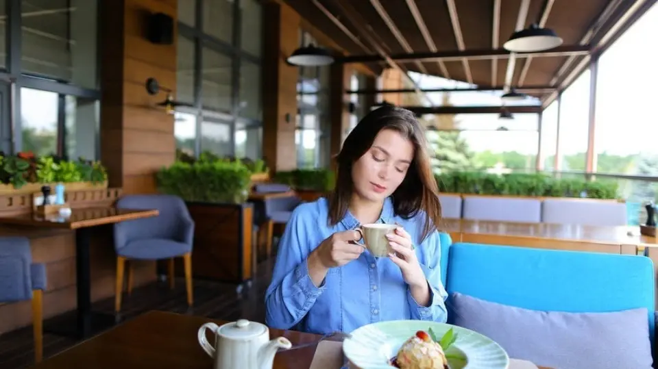 A beautiful woman is enjoying green tea and cake
