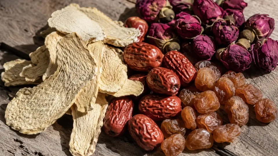 A Rustic Wooden Surface Scattered with Dried Ginger Slices, Red Dates, and Pink Rose Buds A Rustic Wooden Surface Scattered with Dried Ginger Slices, Red Dates, and Pink Rose Buds