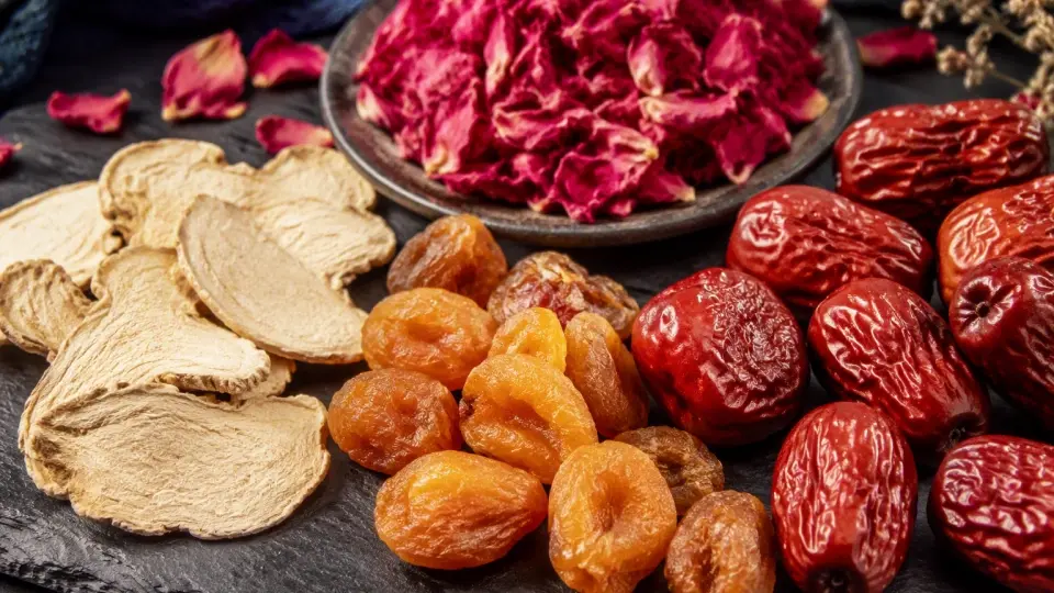 A detailed close-up shot of dried ginger slices, whole red dates, longan pulp, and fragrant rose petals A detailed close-up shot of dried ginger slices, whole red dates, longan pulp, and fragrant rose petals